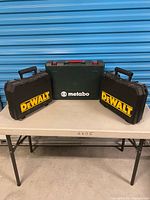 Front view of three cases on table: two DeWALT, one Metabo