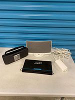 Bose SoundDock, Anker solar charger, RadioShack radio and power adapter on table
