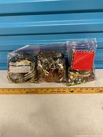 Three resealable bags of assorted costume jewelry and small red jewelry box in front of ruler for scale