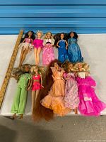 All ten dolls laid out beside ruler for scale