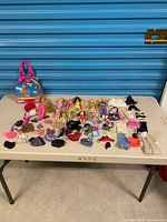 Entire lot on table showing dolls, clothing, backpack and accessories