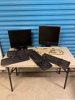 Overall lot: two monitors, six keyboards on folding table
