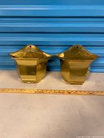 Front view of both brass wall planters showing shape and size reference with ruler
