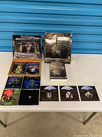 Full lot on table: both boxed sets open, guides, manuals, CDs visible