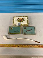 Pipe, two cigarette tins, cigar box, ruler for scale