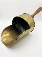 Side view of brass coal scuttle showing scoop mouth and handle