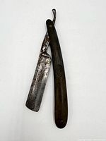 Straight razor fully open showing blade wear and handle