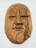 Front view of carved wood Buddha face plaque with bird detail