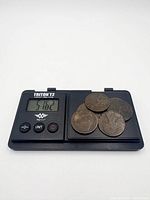 Five coins on digital scale reading 51.02 g