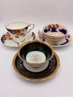 Three collectible tea cup and saucer sets displayed together