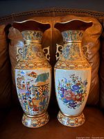 Front view of both Satsuma vases showing figural scene on left vase and floral bouquet on right