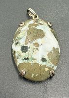 Front view of oval rainforest jasper pendant in prong setting