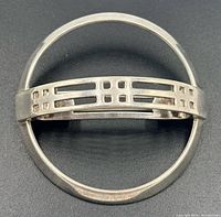 Front view of brooch showing circular shape and grid bar detail