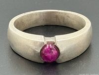 Ring angled to show front with ruby cabochon and band detailing