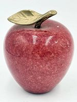 Front view of red stone apple paperweight with brass leaf