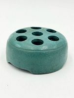 Top angled view of teal ceramic flower frog showing 7 holes and footed side