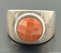 Front view showing bezel-set orange sunstone cabochon and broad face of ring