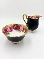 Sugar bowl and creamer side view showing matte black exterior and gold trim