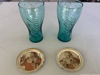 Lot overview showing two green Coca-Cola tumblers and two Santa metal trays