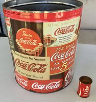 Full view of large Coca-Cola advertising tin with miniature can beside it