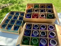 Three cardboard cases filled with multicolour glass candle holders
