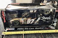 Front and side view of boxed die-cast car showing graphics and scale information