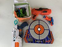 Overview of three dart blasters, electronic target and dart bag