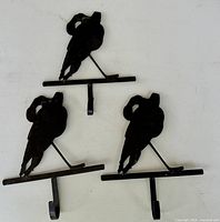 three black wrought iron hockey player hooks laid out