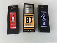 Front view of all three boxed mini sticks showing player names and numbers