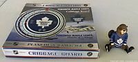 Boxed round Toronto Maple Leafs cribbage board and bear figurine side by side