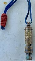 Front view of brass Boy Scouts whistle showing stamp and lanyard