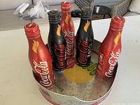 Five aluminum Coca-Cola Torch Relay bottles displayed in the tray