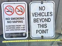 Both metal signs side by side with measuring tape for scale