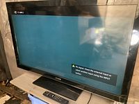 Front view of Sony Bravia TV on stand with remote visible