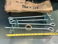 Four steel ground anchors and damaged box with measuring tape