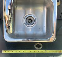 Top view of stainless sink showing drain and tape measure indicating width