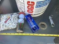 Overall view of bucket, tees bag, tube, Dunlop sleeve, multi-tool and tape on table