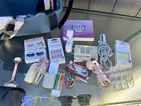 All items laid on table including sunglasses, facial roller, nail sets, eyelashes, hair tools, organizer
