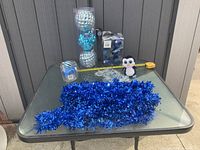 All items displayed on table: garlands, ornaments tube, bagged ornaments, striped ornament, plush penguin