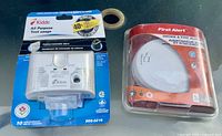 Front view showing both sealed alarm packages: Kidde CO alarm and First Alert smoke alarm