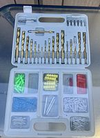 Open carry case showing drill bits and screwdriver bits in upper tray, wall anchors and screws in lower tray
