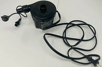 Full view of black electric air pump with power cord and nozzle adapters visible