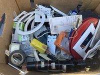 Overview of box showing assorted electrical hardware, wall plates, plug, tape