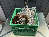 Milk crate filled with tangled white-wire mini lights and tinsel garland on glass table