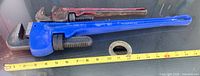 Two pipe wrenches laid beside tape for scale, showing overall sizes