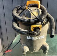 Front view of Shop-Vac showing hose, logo, and wheels