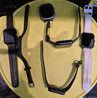 Front view of five smart watches on yellow surface