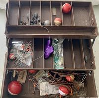Open tackle box showing upper and lower trays filled with floats, sinkers, lures, leaders