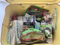 Top view of open tin showing various packaged and loose fishing items