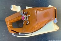 Side view of closed Pocket Fisherman showing brown plastic body and cream rod tip